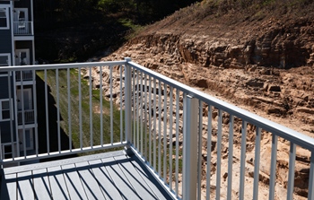 A white railing on a balcony overlooks a rocky hillside.